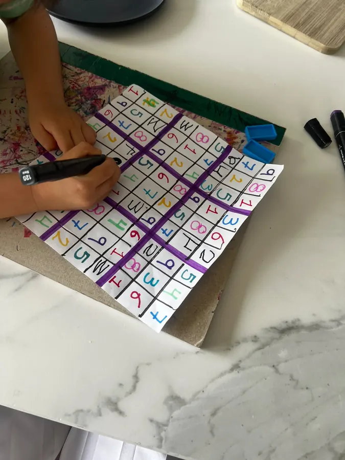 Una niña llena un sudoku de números de colores hecho a mano